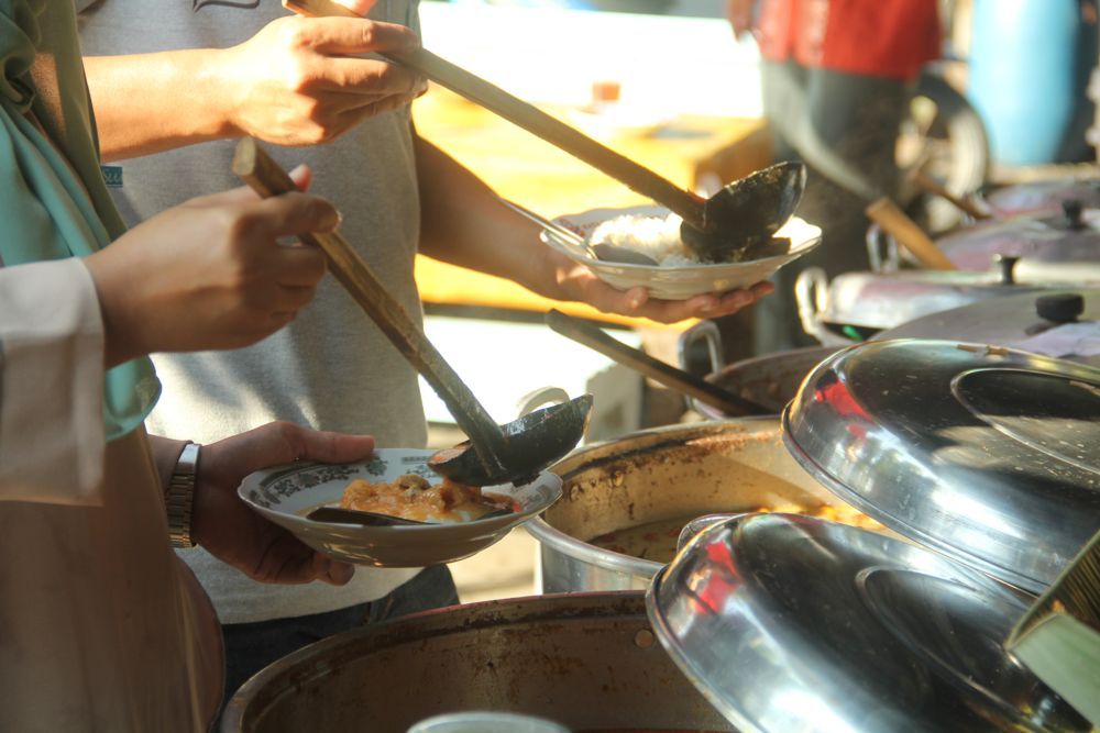Gambar pengunjung menikmati bubur Imogiri dengan mengambil sendiri makanannya, menggunakan sistem prasmanan.